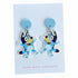 A pair of cartoon dog stud earrings displayed on a white backing card. The earrings feature a light blue circular stud and a dangling die-cut character charm in shades of blue, yellow, and black, with a small gold-tone ring at the top.